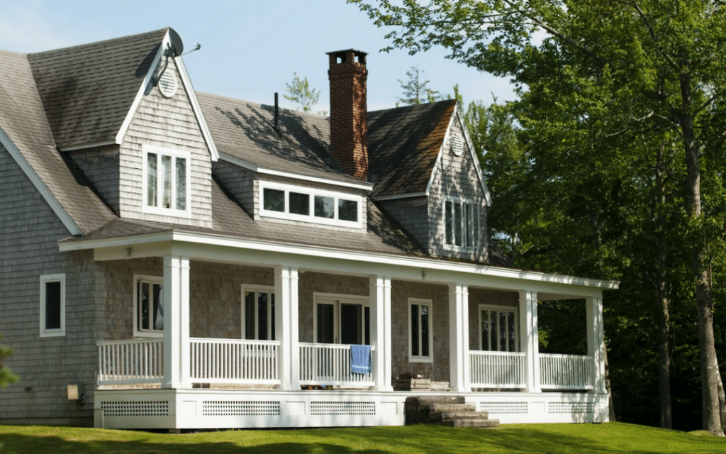 Modern house with a big front porch and big trees on the side of the house needing tree maintenance